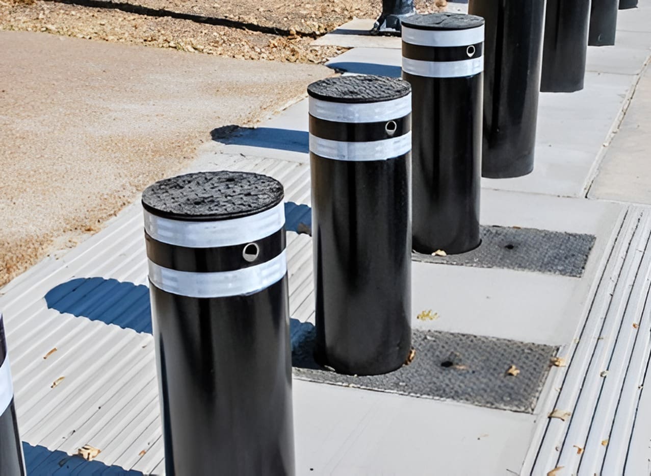 A row of black and white metal posts on the sidewalk.