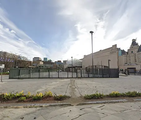 A large empty lot with a fence and building in the background.