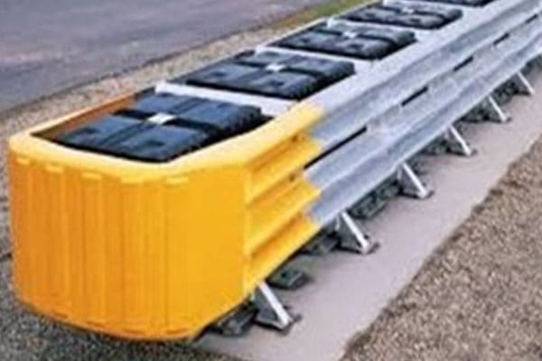 A yellow and silver barrier on the side of a road.