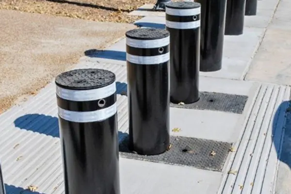 A row of black and white bollards on the sidewalk.