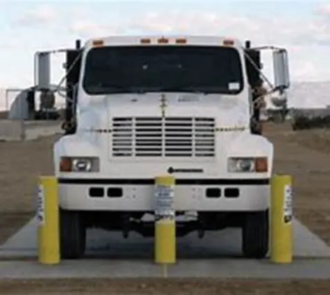 A white truck parked in front of some yellow posts.